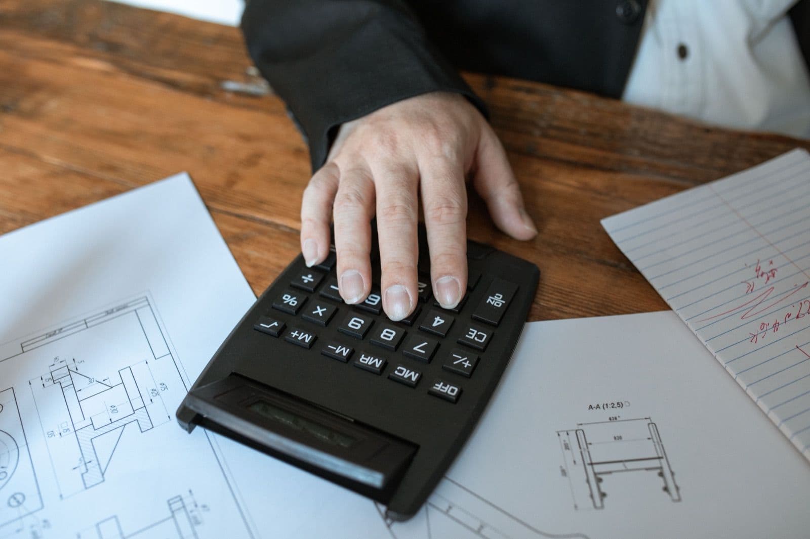 Engenheiro montando orçamento de obra com planilha e calculadora